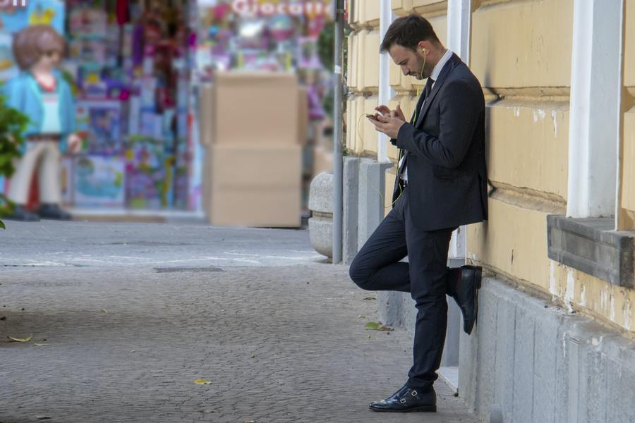 Man in suit listening to music standing against wall