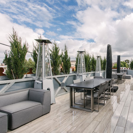 Outdoor patio at Deskplex Office Space Hawthorn Richmond Abbotsford with modern tables, chairs, outdoor heaters, and potted trees. Clean, comfortable, and stylish