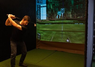 Man playing golf in front of an indoor golf simulator at DeskPlex Office Space Hawthorn Richmond Abbotsford.