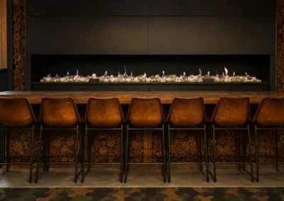 Relaxed breakout and lounge area at DeskPlex Hawthorn featuring a long fireplace, timber finishes and casual seating, giving members an inviting space to meet, work informally or take a break during the day.