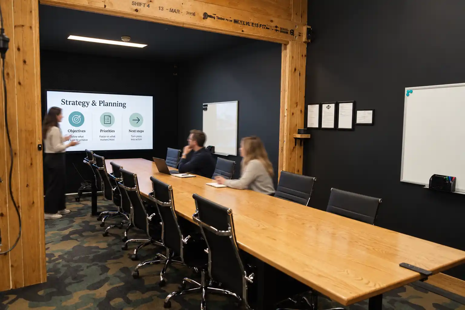 Spacious boardroom at DeskPlex Hawthorn with a large timber conference table, presentation screen and whiteboards, providing a professional setting for board meetings, presentations, workshops and larger team sessions.